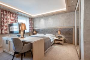 奥伯古格尔Hotel Alpina deluxe的酒店客房配有一张床、一张书桌和一张书桌。