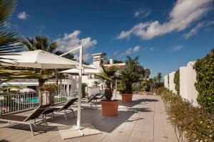 伊斯基亚德察门格利夫托酒店的一个带椅子和遮阳伞的庭院和一个游泳池