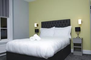 普雷斯顿The Spring Bank APARTHOTEL的卧室配有一张带白色床单和枕头的大床。
