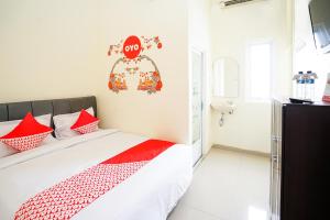 泗水OYO 223 Penginapan Nabila Syariah的一间卧室配有红色和白色枕头的床