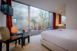 马拉喀什里亚德马拉喀什旅馆的一间卧室设有一张床和一个拥有盆栽植物的大窗户
