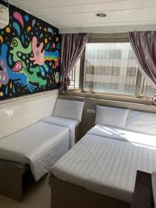 香港嘉應賓館HAKKAS GUEST House的墙上画画的房间里设有两张床