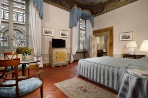 佛罗伦萨Palazzo Niccolini al Duomo Residenza D'Epoca的一间卧室配有一张床和一台电视。
