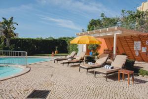拉戈斯马尔阿祖尔别墅酒店的一组椅子和一把遮阳伞,位于游泳池旁
