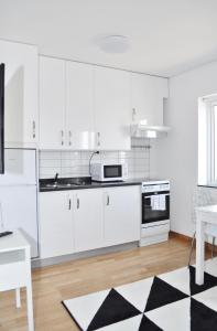 隆德Apartments Lund的厨房配有白色橱柜和黑白地毯。