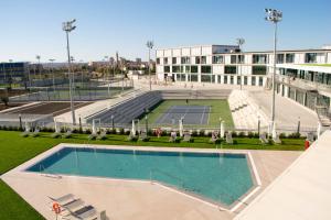 马纳科尔Rafa Nadal Residence的一座空水池,在一座大楼前设有一个网球场