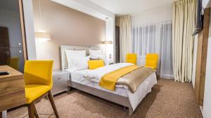 锡比乌Dumbrava Residence的一间卧室配有一张床和两张黄色椅子