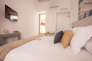 塞维利亚Lukanda Mariana的卧室配有带枕头的白色床和电视。