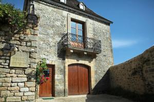 贝纳克和卡泽纳克La Cafourche的一座石头建筑,设有两扇门和一个阳台