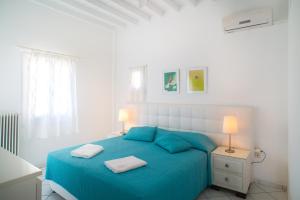 图罗斯Adikri Villas & Suites的一间白色卧室,配有一张蓝色的床和两盏灯