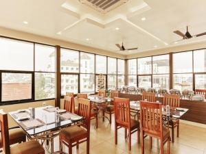特里凡得琅Treebo Trend Goodland Residency的餐厅设有桌椅和大窗户。