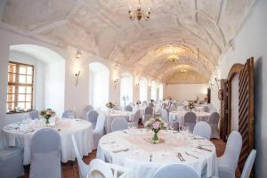 布兰纳zámek Kolštejn - hotel Chateau Goldenstein的宴会厅配有白色的桌子和白色的椅子
