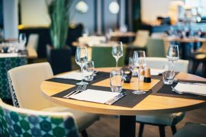 斯特拉斯堡Hôtel Restaurant Athena Spa的一张带酒杯和餐巾的木桌