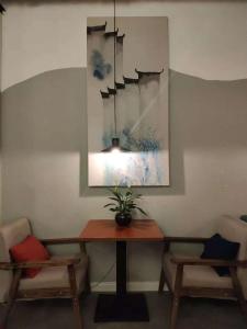 苏州苏州蓝色大门青年旅舍的餐桌,配有两把椅子和盆栽植物