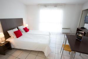 梅里尼亚克All Suites Appart Hôtel Bordeaux Mérignac - Aéroport的卧室配有带红色枕头的大型白色床
