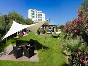 里乔内Hotel Sarti的草原上带椅子和桌子的帐篷