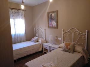 Arroyo de la LuzCasa Rural La Santiaga的一间卧室设有两张床和窗户。