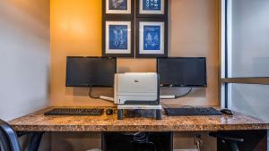 里贾纳Seven Oaks Hotel Regina的一张桌子,配有两台电脑显示器和一台打印机
