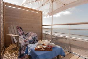 孔卡尔诺柯默尔酒店的阳台配有桌子、椅子和雨伞。