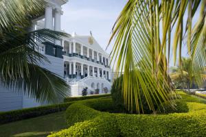 海得拉巴泰姬陵法拉克奴玛宫酒店的一座白色的建筑,前面有棕榈树