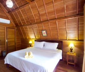 珀尼达岛Nusa Penida Pudak Nature Bungalow的卧室配有白色的床和2条毛巾