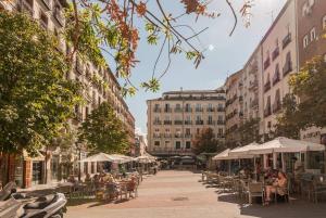马德里Explore Madrid from a warm apartment with patio at a newly refurbished manorial building的一条带桌椅的城市街道