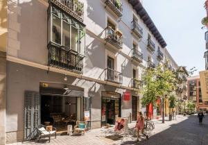 马德里Explore Madrid from a warm apartment with patio at a newly refurbished manorial building的走在建筑物前的街道上的女人