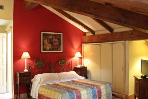博洛尼亚德拉佩里旅馆的一间带红色墙壁、一张床和电视的卧室
