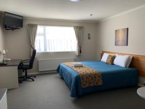 福克斯冰川高峰酒店的一间卧室配有一张床、一张书桌和一个窗户。