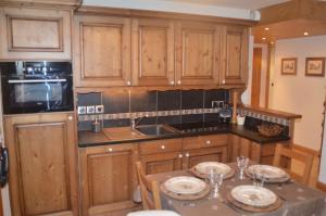 萨莫安斯ECRINS ETOILE C9的厨房配有木制橱柜和一张带盘子的桌子。