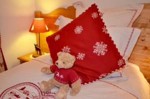 萨莫安斯ECRINS ETOILE C9的一只泰迪熊坐在床上,带红色枕头