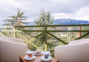 艾克斯莱班马尔利奥布洛斯别墅Spa酒店的阳台配有两把椅子和一张桌子,上面有杯子