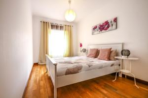 CacilhasApartamento Tejo的卧室配有白色的床和窗户。