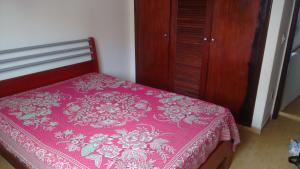 瓜拉派瑞Apto Guarapari - Praia do Morro - 50 m da praia的一间卧室配有一张粉红色的床和木柜