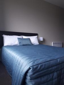 提马鲁诺斯帕克汽车旅馆的一张带蓝色毯子和白色枕头的大床