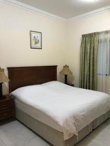 沙迦Al Majarah Residence的一间卧室设有一张大床和一个窗户。