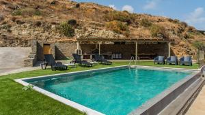 SinétionAnastasis Luxury Villa Andros With Heated Pool的一个带椅子的庭院和房子的游泳池