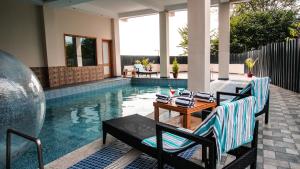 达兰萨拉D'Polo Club & Spa Resort的游泳池旁设有两把椅子和一张桌子