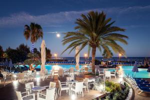 科斯塔特吉塞特贵司普拉亚大酒店的一个带桌椅的游泳池,以及棕榈树