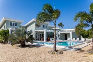 棕榈滩Malmok Beach Break Villa的一座带游泳池和棕榈树的房子