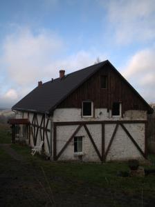 SierpnicaDziki domek的一座在田野上带黑色屋顶的旧谷仓