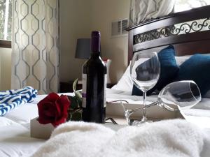 下博克特Casa Mirango Boquete的床上有一瓶葡萄酒和两杯酒