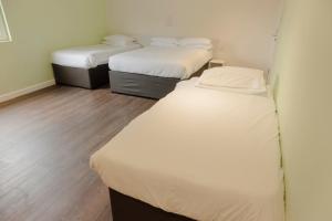 唐克斯特Primelodge Doncaster的小型客房铺有木地板,配有两张床。