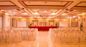 碧瑶Benguet Prime Hotel的宴会厅配有白色椅子和红色桌子
