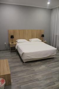 阿斯塔纳Hotel Inju Hills的卧室配有一张白色的大床和两张桌子