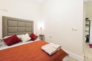 马德里瑞拉托雷斯街公寓的一间卧室配有一张带红色和白色枕头的大床