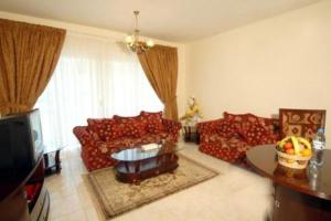 迪拜皇家广场公寓酒店的客厅配有红色沙发和电视