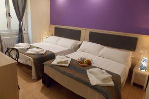 米兰Hotel Midtown Milano的酒店客房带两张床、毛巾和一碗水果