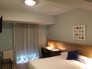 塞拉诺瓦Hotel Celanova的酒店客房配有一张床、一张书桌和一张书桌。
