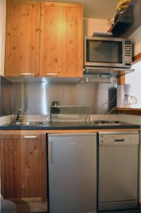 瓦尔弗雷加斯Les Melezets 1的厨房配有木制橱柜、微波炉和洗碗机。